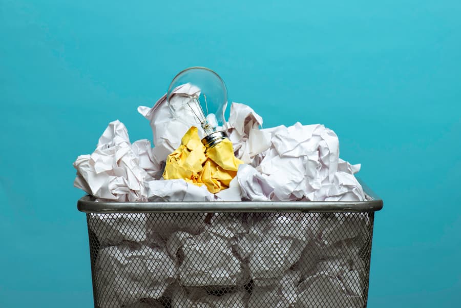 Trash can with paper and light bulb